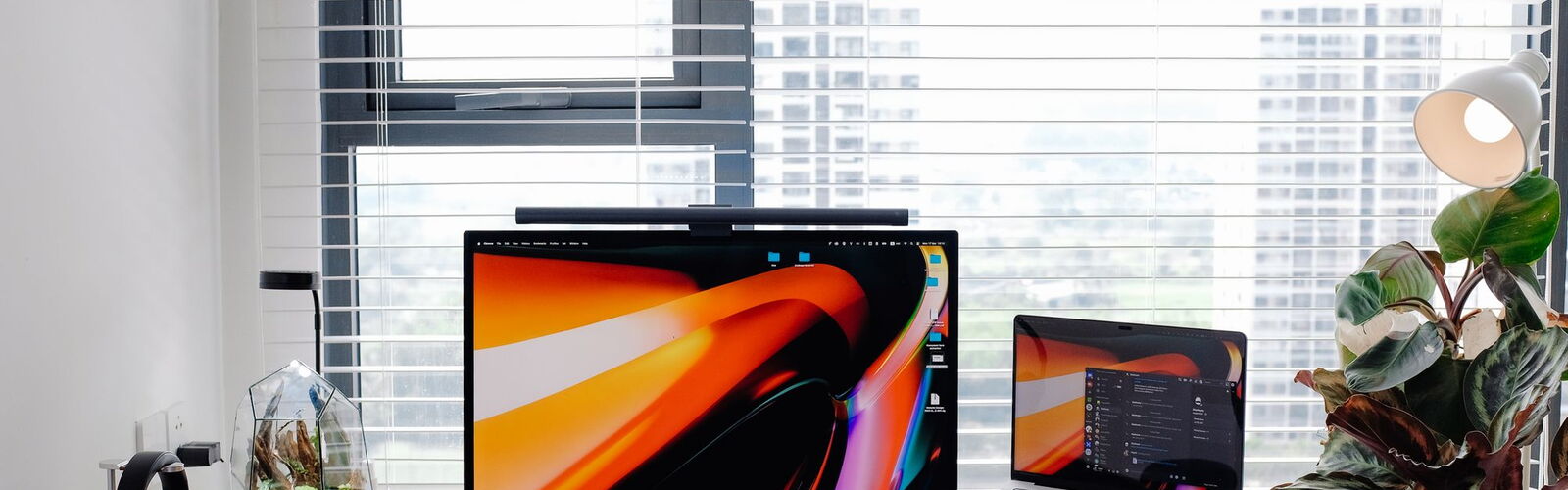 Aufgeräumter Schreibtisch mit Laptop und Monitor